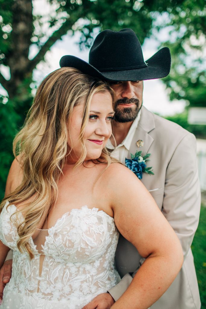 groom cuddles bride from behind in the shadow of a tree in Hasty AR