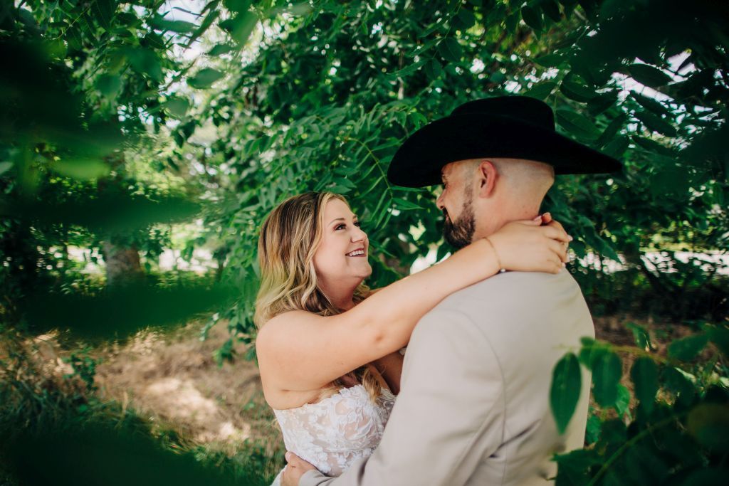 bride gazes adoringly at groom surrounded by thick green foliage on her wedding day