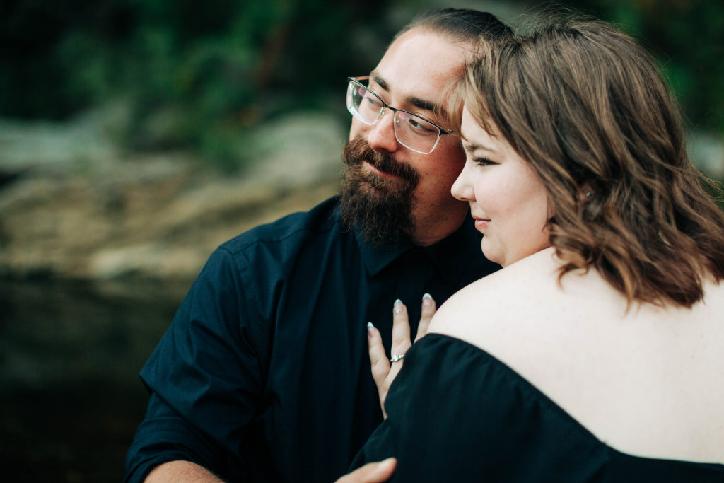a couple embraces by a river while gazing at the horizon