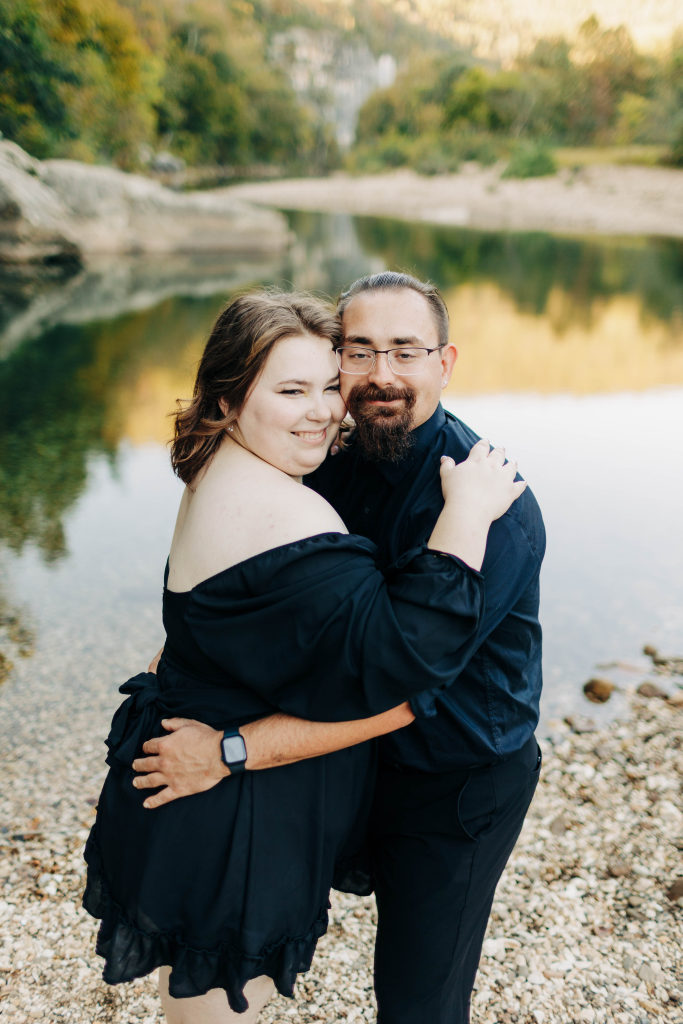 a couple embrace with a reflective pool of water in the background by Steel Creek