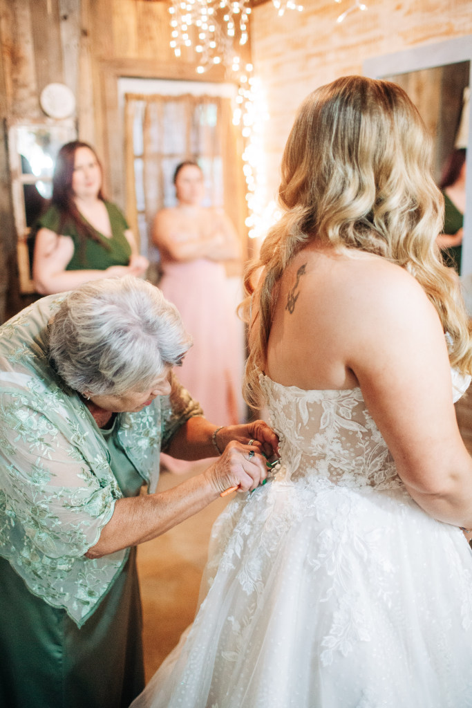 grooms mother helps do up the bride's dress in Hasty AR