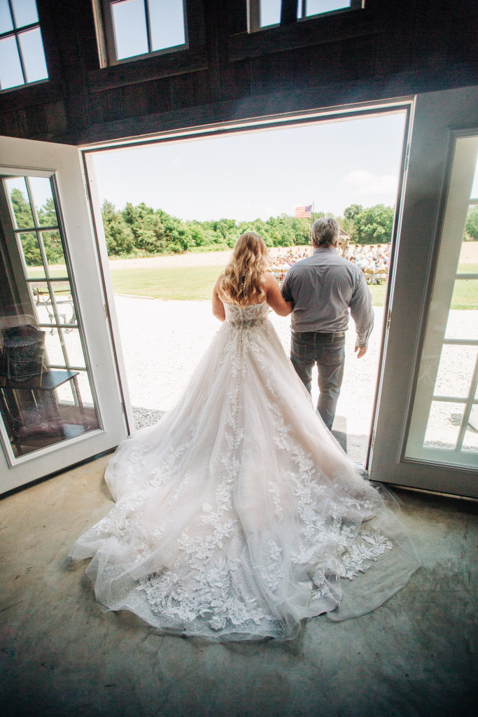 bride gets ready with her dad by an open door to walk down the isle