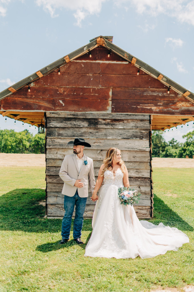 bride and groom look opposite directions in front of a wooden cabin