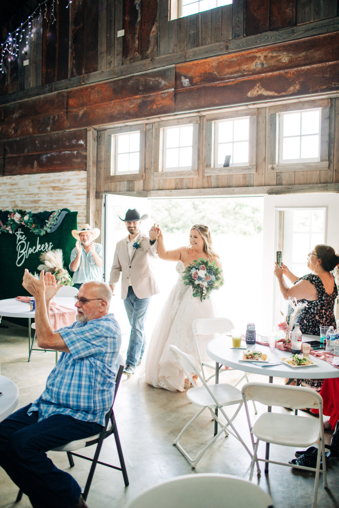 bride and groom enter the reception smiling