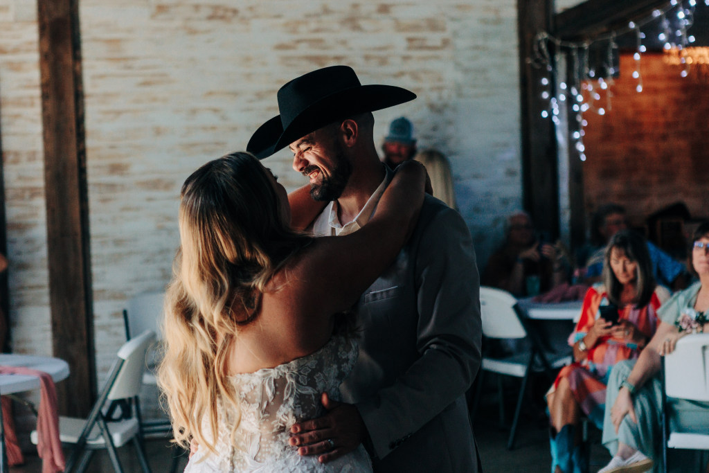 groom smiles while dancing with the bride