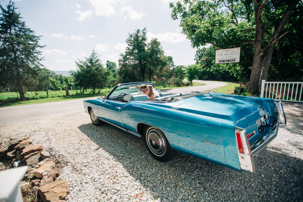 couple kiss in their blue cadillac before they leave the White Barn