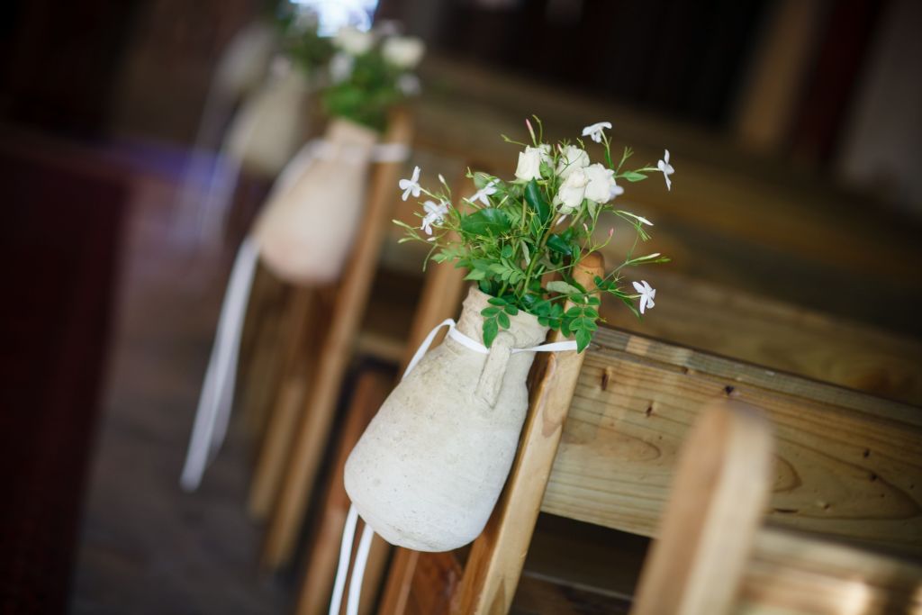 whimsical flower arrangements with white roses adorn the ends of the wooden pews in a chapel